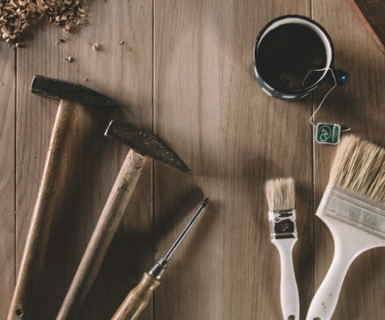Holzarbeiten Werkzeuge auf einem Tisch, einschließlich Hammer, Pinsel und Tasse. Handwerker. Handwerk. Reparaturen.