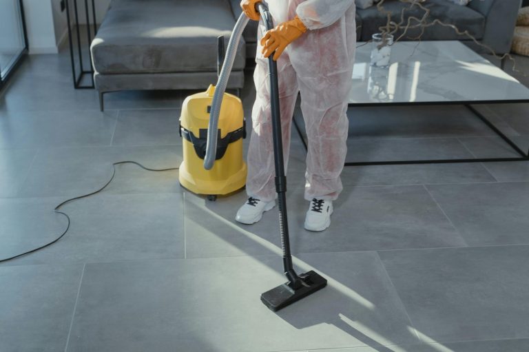 Person mit Staubsauger reinigt einen modernen Raum mit grauem Boden.