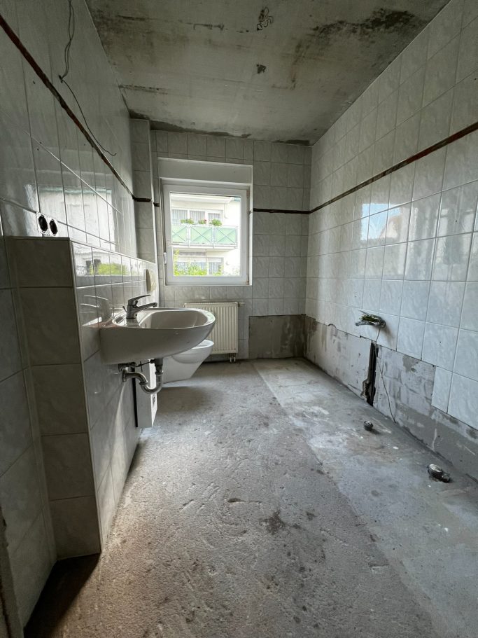 Leeres Badezimmer mit Fliesen, zwei Waschbecken und Fenster, aber ohne Möbel.