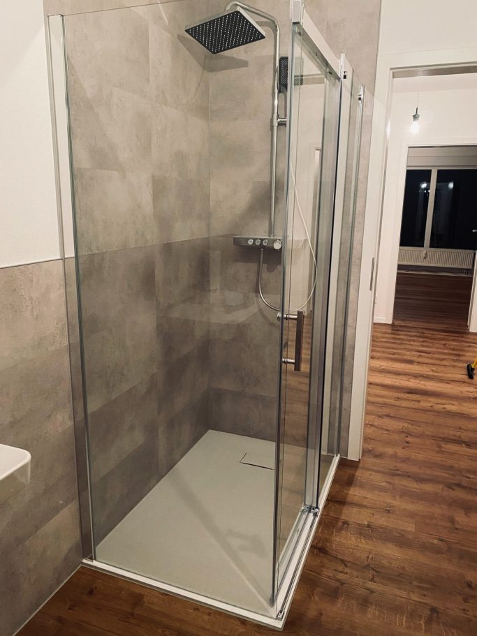 Moderne Dusche mit gläserner Trennwand und eleganter Holzfußboden.